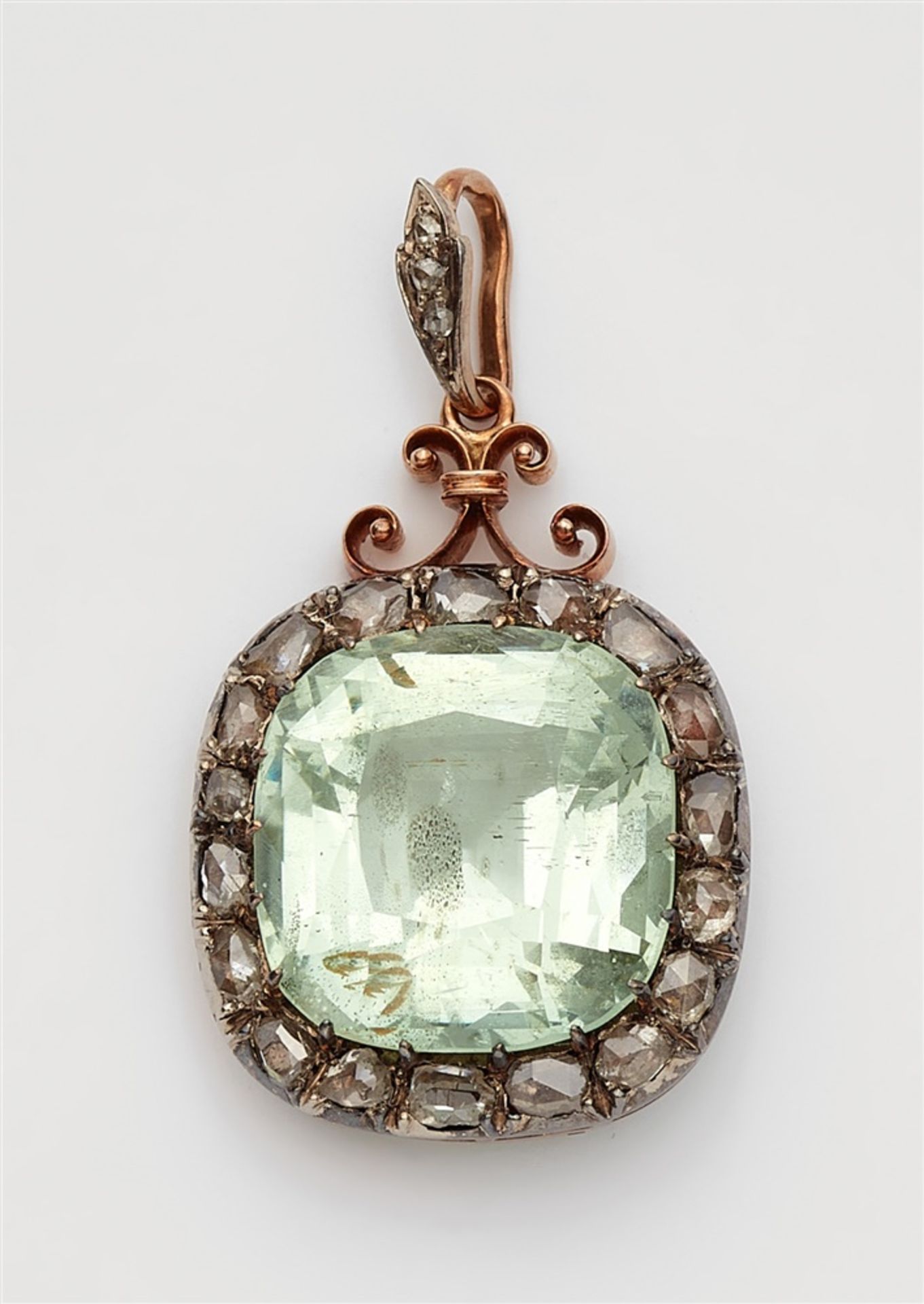 A Belle Epoque beryl pendantA silver and 14k red gold cluster set pendant with a large pale green