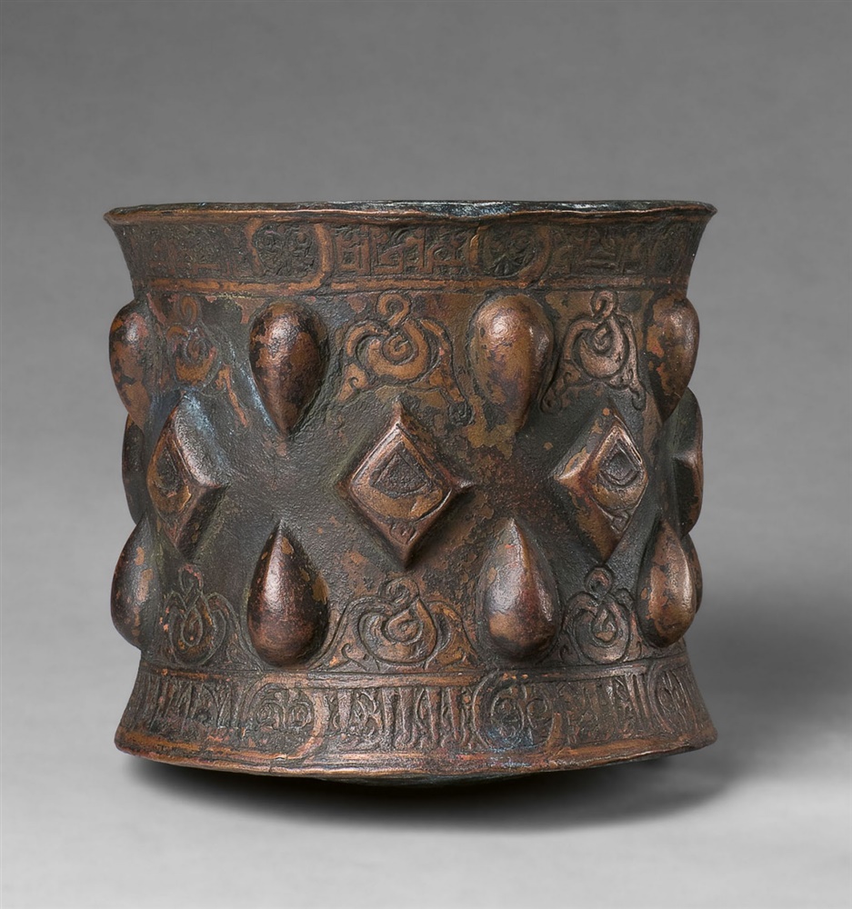 An Islamic mortarChased cast bronze, presumably with sintered polychromy. Of cylindrical form with