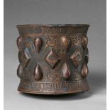An Islamic mortarChased cast bronze, presumably with sintered polychromy. Of cylindrical form with