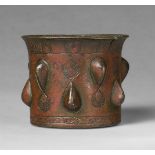An Islamic mortarChased golden brown cast bronze with applied copper studs and red pigment. Of