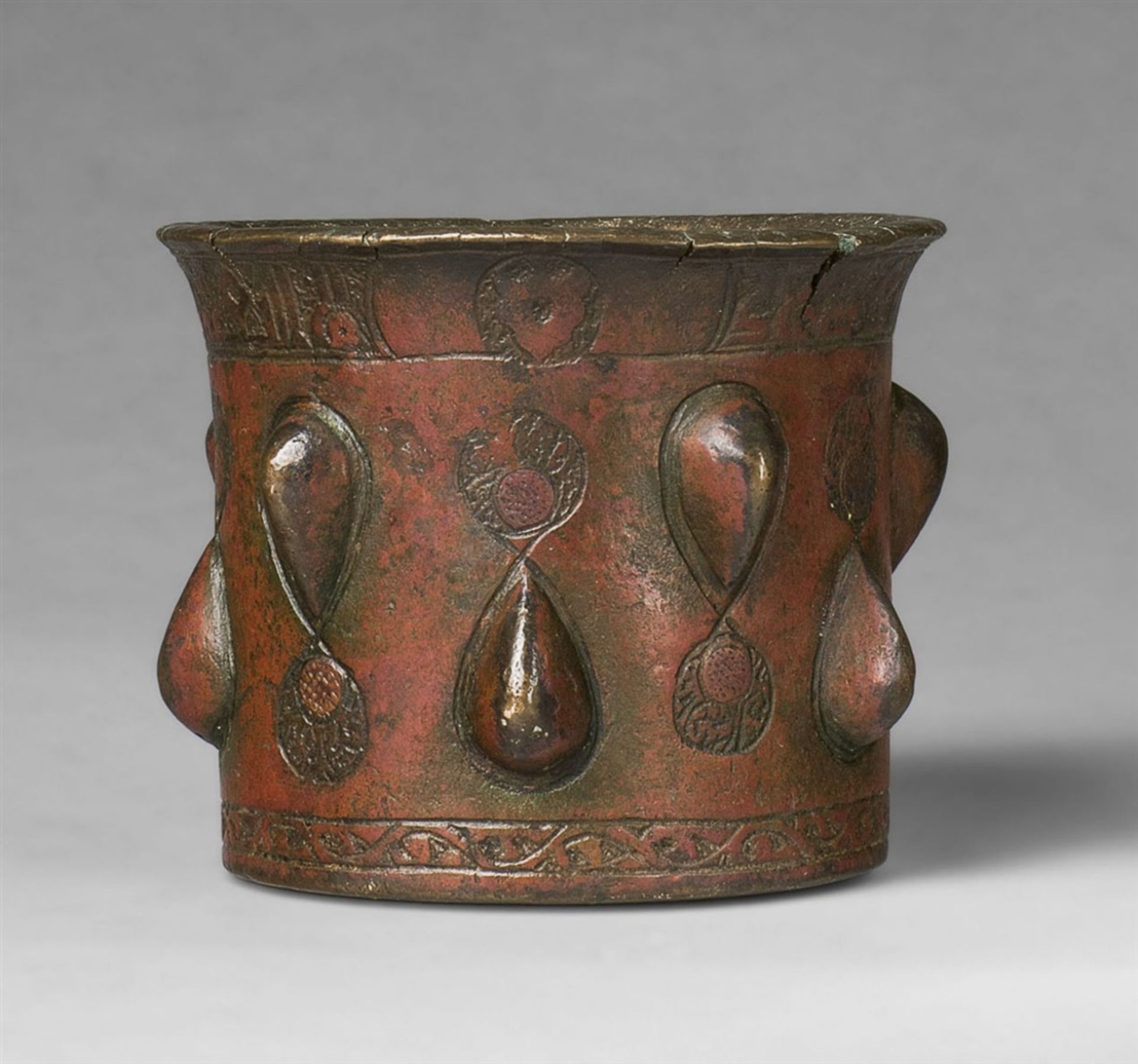 An Islamic mortarChased golden brown cast bronze with applied copper studs and red pigment. Of