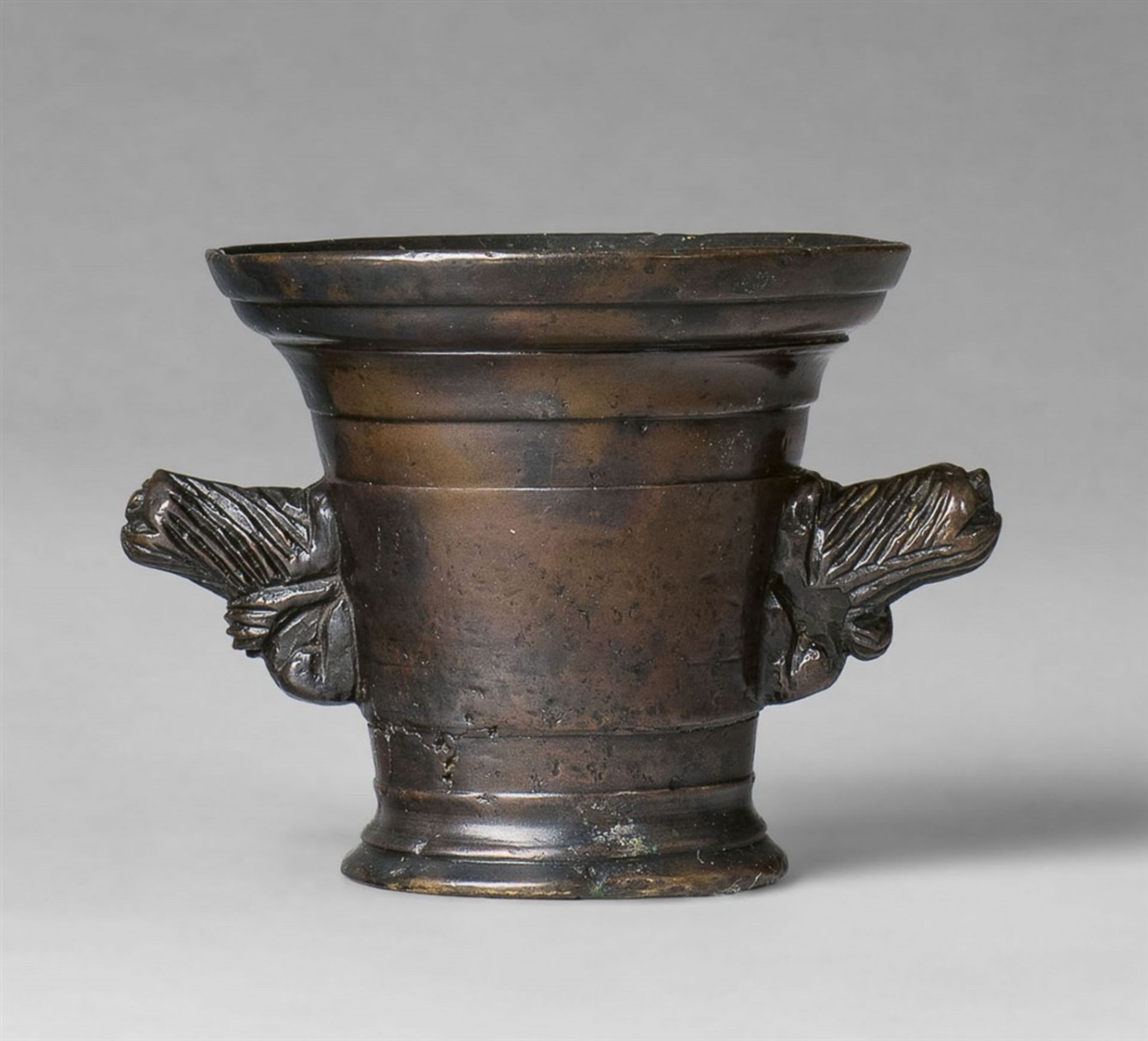 A small mortar with lion handlesCast bronze with golden brown patina. The handles formed as two