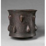 An Islamic mortarCast and chased bronze, possible sintered early polychromy. Cylindrical form with