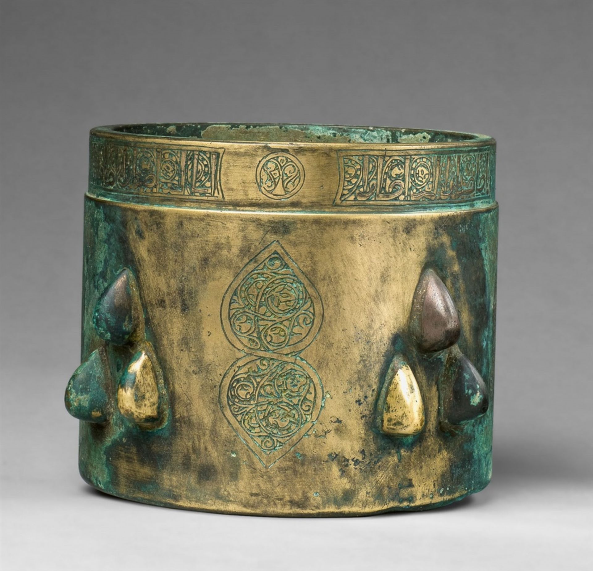 An Islamic mortarYellowish golden chased bronze. Cylindrical form with slightly waisted upper rim.