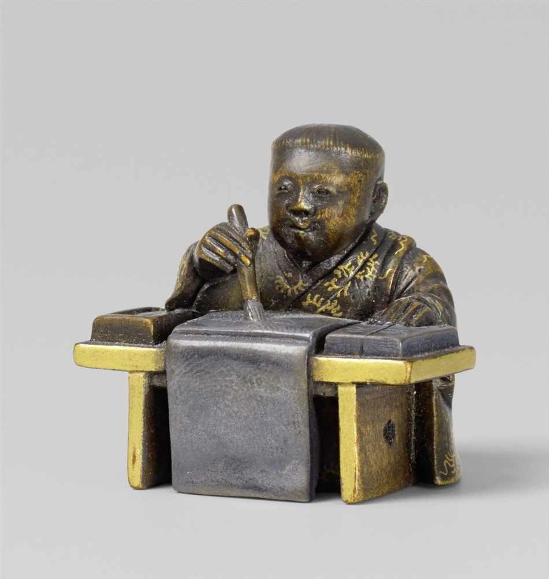 A partly lacquered wood netsuke of a boy writing. 2nd half 19th century