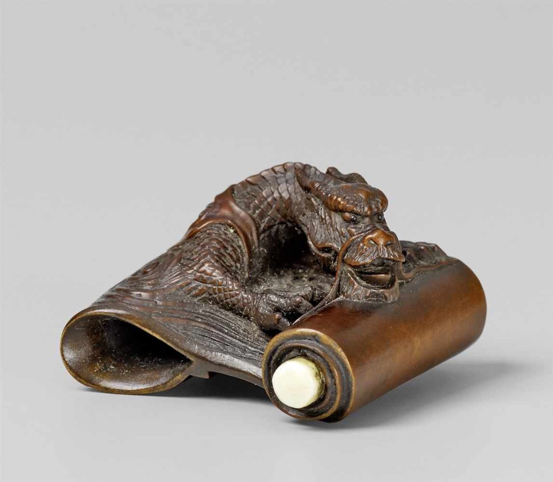 A boxwood and ivory netsuke of a dragon. Late 19th century