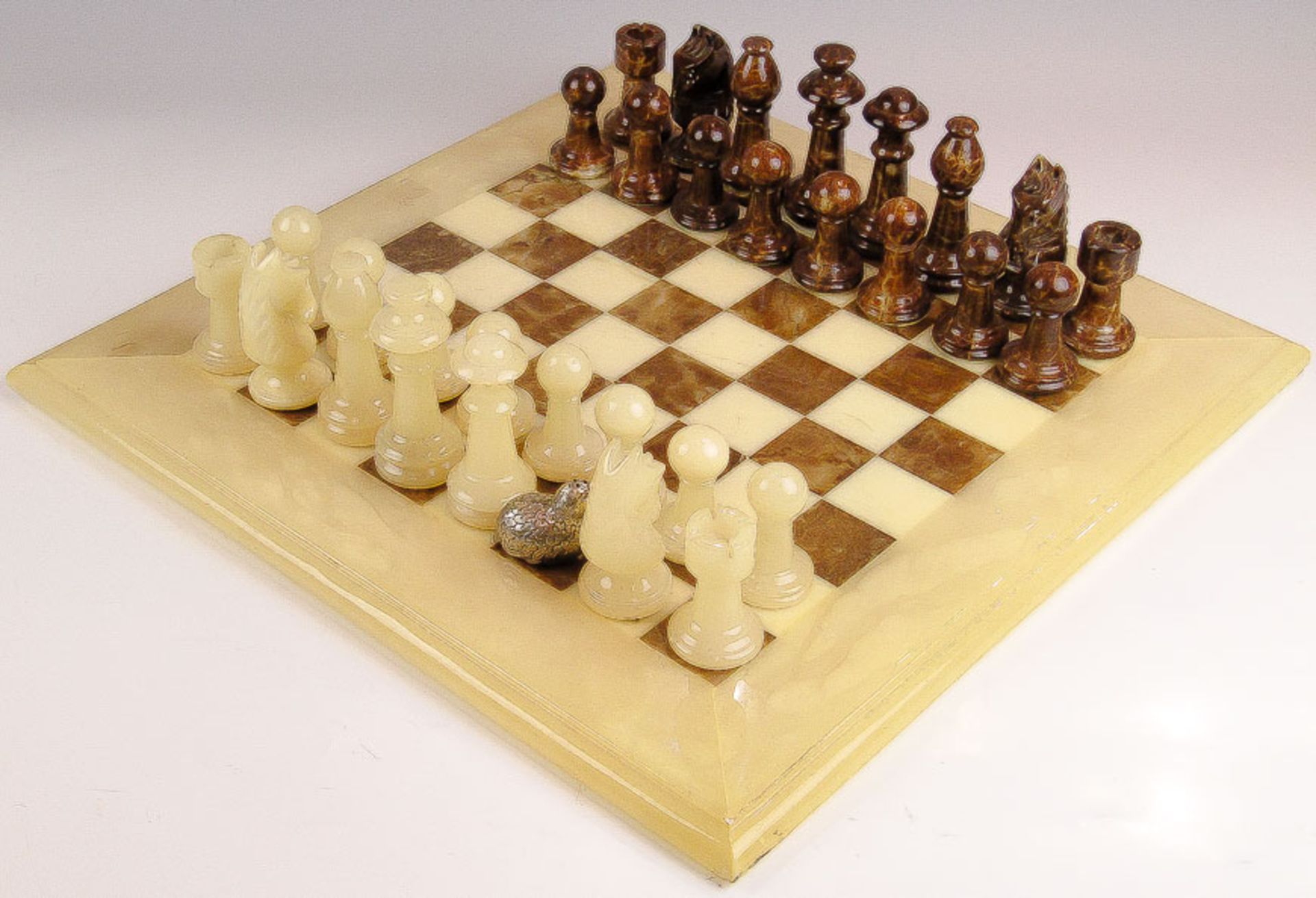 Schachbrett mit 31 FigurenWeißer und brauner Onyx. 47×47 cm, König H. 10 cm. (Weißer Läufer fehlt,