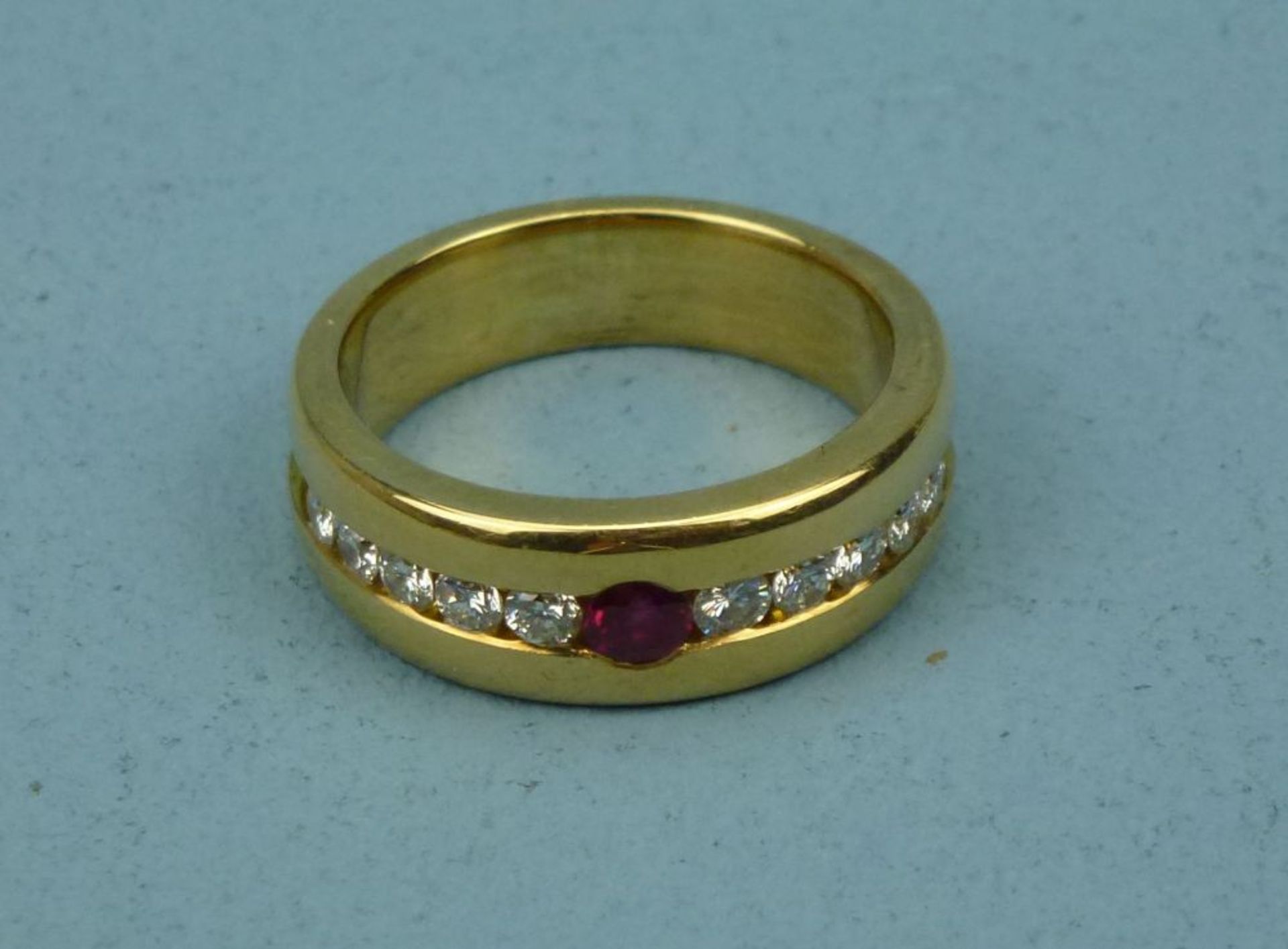 Ring, 750er Gelbgoldvertieft gefasster facettierter Rubin flankiert v. 10 Brillanten (ges. ca. 0,