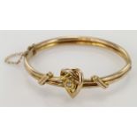 9ct yellow gold hollow hinged bangle with box clasp and safety chain, central woven heart design