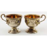 Pair of white metal cups raised on a pedestal base (possibly Russian), each with gilt handle and