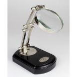 Anglepoise magnifying glass on a wooden base, plaque reads 'Watts and Sons Ltd Opticians, London