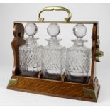 Tantalus. A walnut three decanter tantalus by Betjemann (no. 1200) , unlocked (key missing),