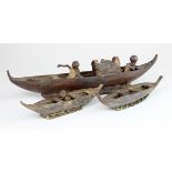 Three hand carved canoes, two containing carved figures, date unknown, possibly from an Egyptian