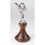 Spirit of Ecstasy car mascot mounted on a turned wooden base, mascot stamped 'Rolls Royce Motors