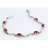 9ct white gold bracelet set with six stations comprising an oval ruby and two diamond points,