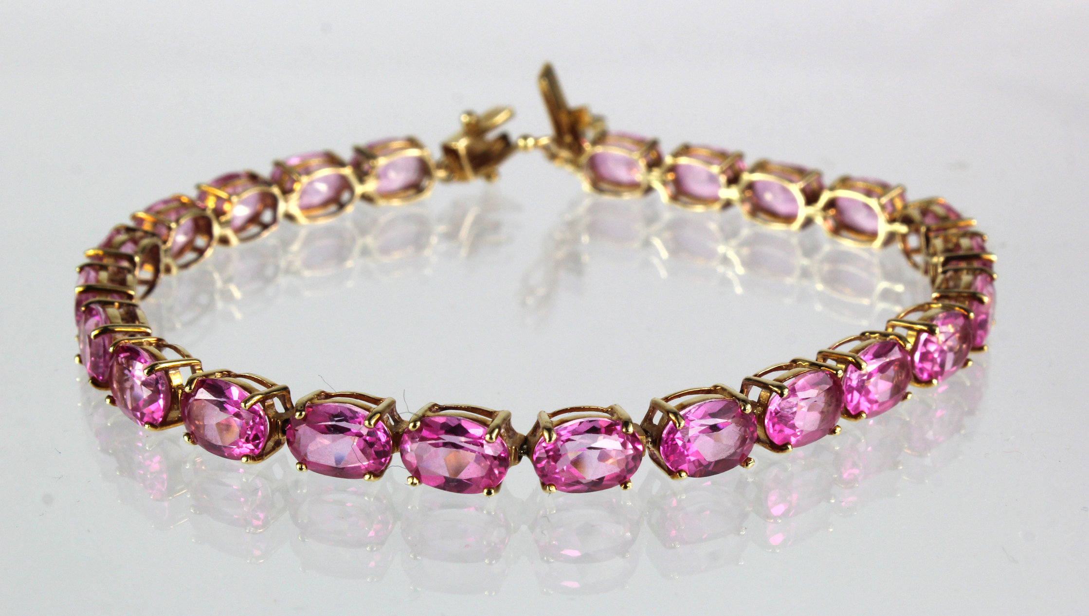 9ct yellow gold "tennis" bracelet set with oval pink Sapphire stones with box clasp and safety,