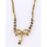 Tests as high carat yellow gold necklace with feature bow decoration set with rubies and emeralds