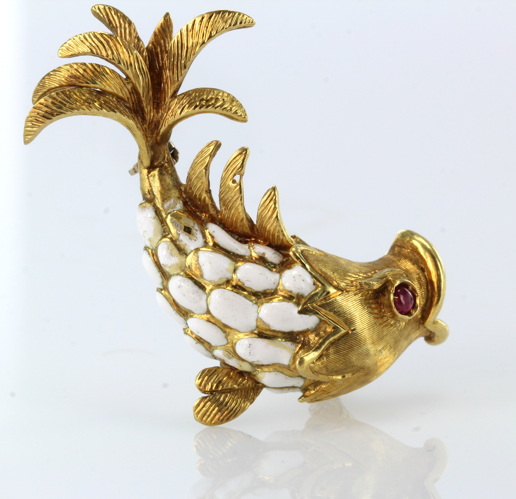 18ct yellow gold brooch in the shape of a leaping fish with a ruby eye and white enamel scales,