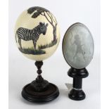 Hand painted Ostrich egg depicting a zebra beneath a tree, on a turned ebony stand, total height