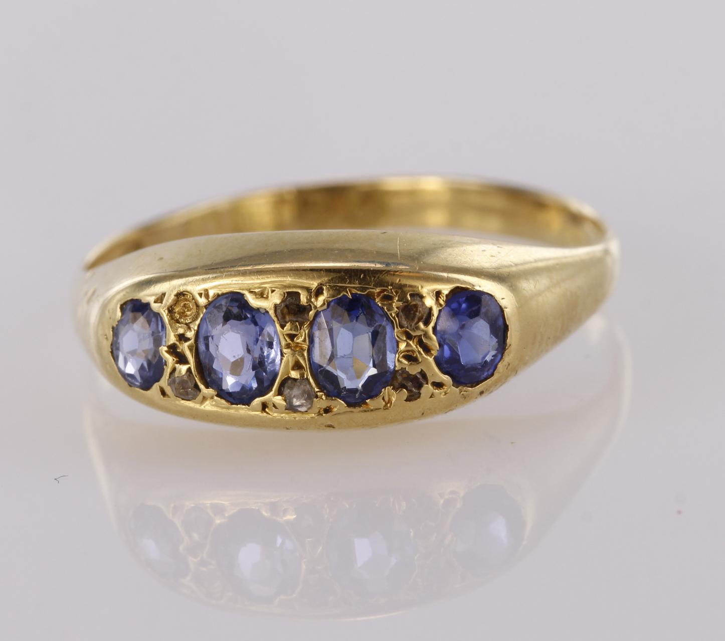 18ct yellow gold graduated sapphire four stone ring with diamond points, finger size P, weight 2.6g