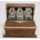 Carved oak tantalus with brass mounts & handles, with three cut glass decanters (some chips to