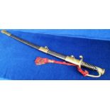 Sword, made in India, blade length 80cms housed in a scabbard, decorative brass hilt with red silk