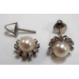 Pair of platinum diamond and pearl earrings, the large central pearl surrounded by ten small