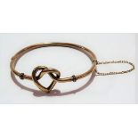 Early 20th Century 15ct gold hinged hollow bangle with heart shaped knot, stamped 15ct, weight 7.