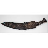 A Kukri with carved bone inlaid handle, the leather covered sheath with brass embossed mount and