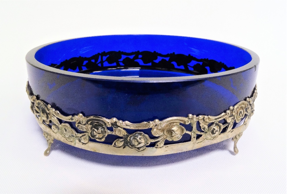 White metal and blue cobalt glass dish, the white metal pierced and embossed with full scrolls and