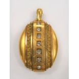 Victorian yellow metal oval locket, the front with a band design and set with seven white