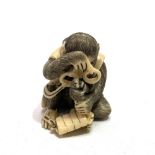 A good Japanese Meiji period ivory netsuke carved as a seated monkey holding spectacles, looking