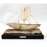 An early 20th century horn and ivory model of a sail boat upon carved wood base, width 20cm.