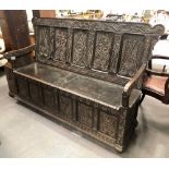 18th Century carved oak panelled box seat settle, the back with carved stylised animals and