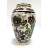 A Persian tin glazed vase, foliate decorated upon a cream ground, signed to the base Katona Mihaly