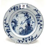 An 18th century English Delft dish decorated to the centre with a Ho Ho bird on a tree stump with