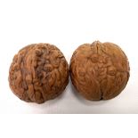Two Chinese carved walnuts, each profusely carved with figures and dragons.