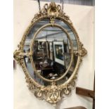 Good Victorian oval gilt gesso moulded cream and parcel gilt decorated wall mirror, height 138cm.