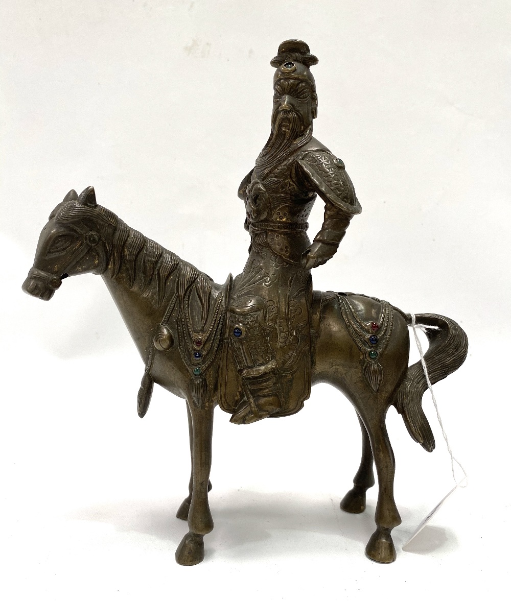 An oriental bronze modelled as a warrior on horseback, inset with glass cabochons (some missing),