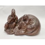 A Chinese stoneware Yixing group modelled as a reclining jovial Buddha against a pillow with