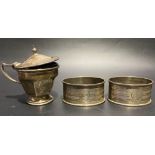 Pair of silver engine turned napkin rings together with a silver pedestal lidded mustard pot, weight