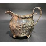 Edwardian silver foliate embossed cream jug with C scroll rim raised on four ball feet, Birmingham