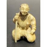 Meiji period ivory carved netsuke in the form of a kneeling gentleman with stick, height 4cm