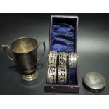 A silver hallmarked twin handled trophy cup together with a silver engine turned compact and a cased