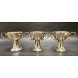 A good set of three Edwardian Art Nouveau three handled pedestal cups by William Aitken, the lobed