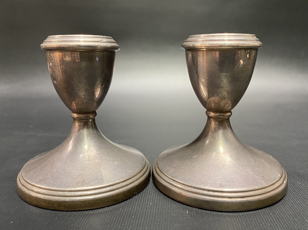 A pair of modern silver squat candlesticks with weighted bases.