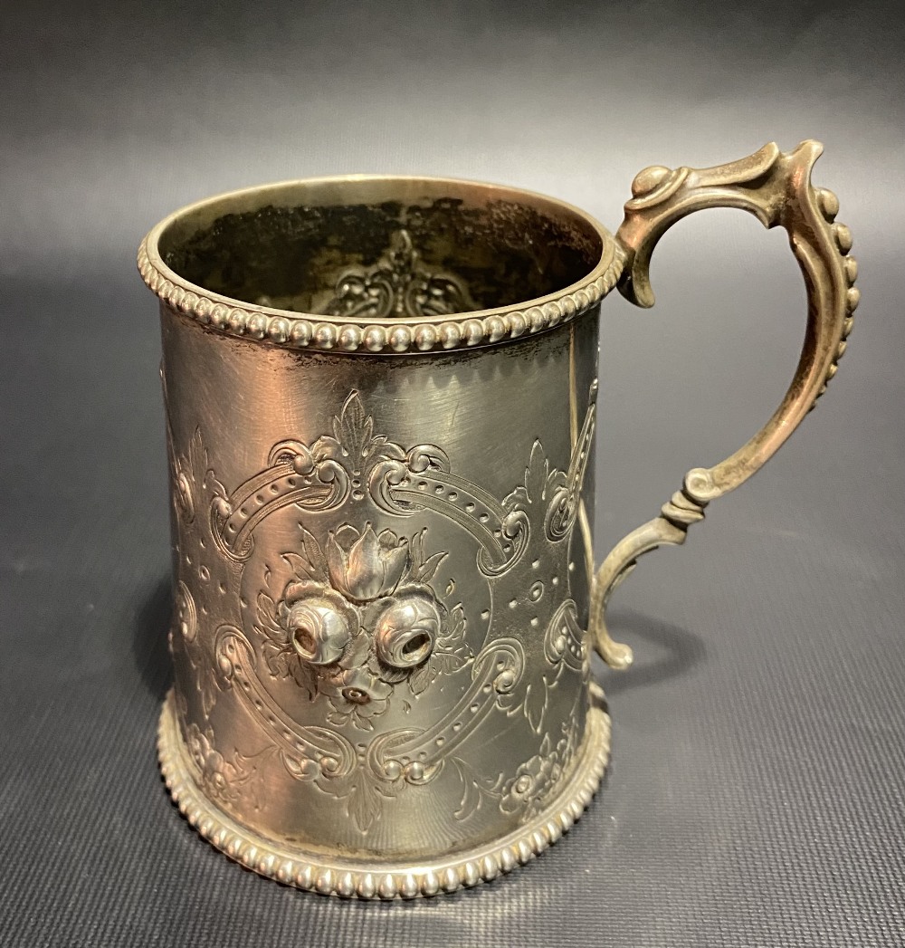 Victorian silver mug with foliate embossed and strapwork design and with beaded rim and base,