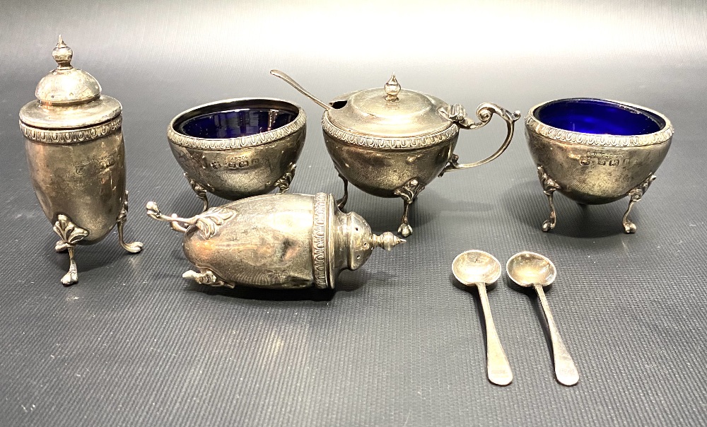 A George V silver five piece cruet set, with three associated cruet spoons, of ovoid form and raised