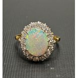 18ct white opal and diamond cluster ring, the opal displaying blue, green, pink and red colours, the