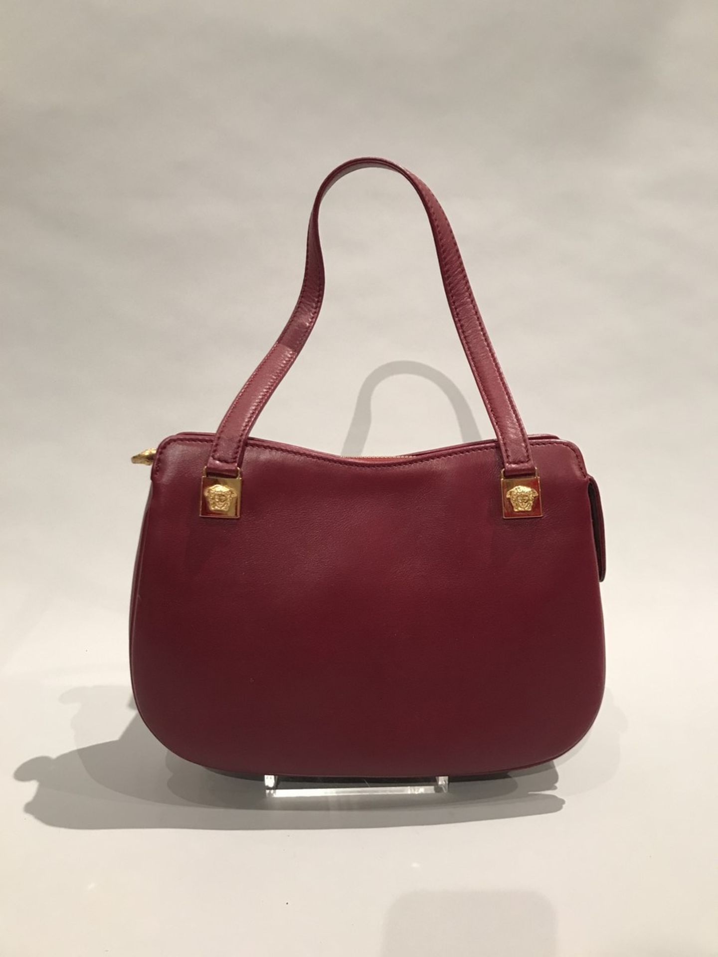 GIANNI VERSACE - SAC porté main en cuir bordeaux. Sigles à tête de méduses en [...]